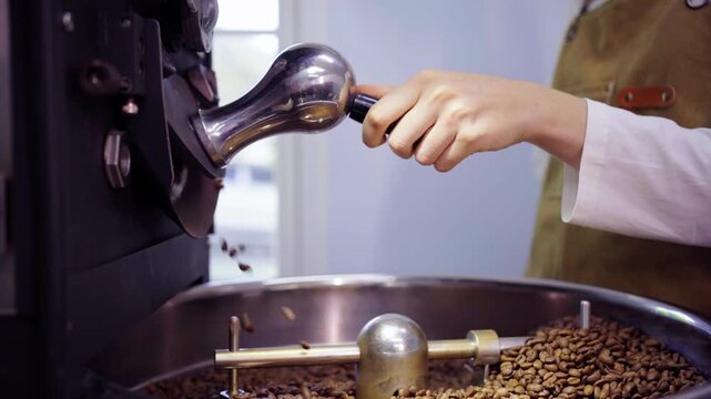 Female roaster opening drum hatch to dump beans in cooling tray