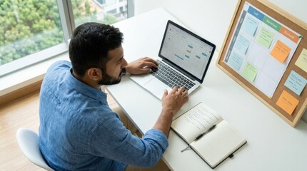Obraz premium Focused young man working on a laptop in a bright modern workspace