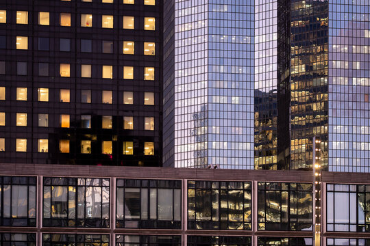 Urban architecture at night layers office building facade reflections through glass windows, while corporate interior floors define a dense city block