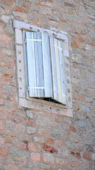 Fototapeta premium White, wood window shutters in textured, multi-colored stone wall