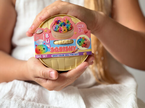 Child holding colorful squishy toy in round package