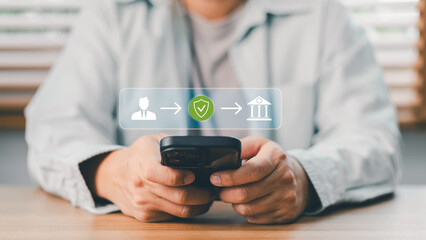 Naklejka premium Close up of person holding smartphone doing secure online mobile banking transaction. Financial technology icon showing safe money transfer from user to bank institution