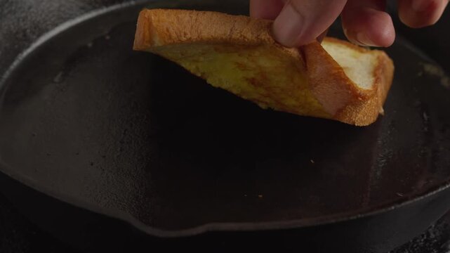 slice of buttered white bread toasting on a hot cast iron skillet