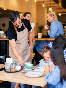 Friendly barista serving hot chocolate to a little boy 