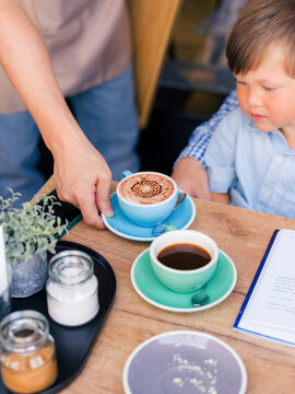 Boy watching waiter serving his drink at cafe 