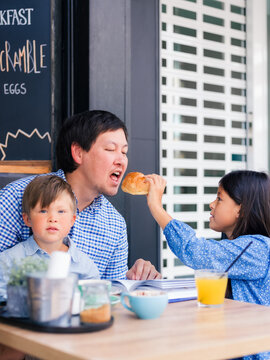 Girl feeding her father at cafe 