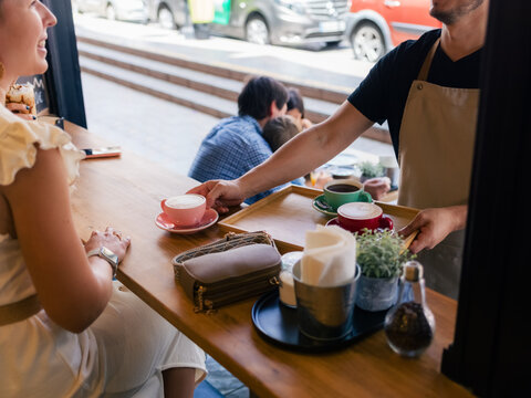 Barista Serves Coffee at Cafe While Customers Enjoy Their Drinks