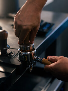 Barista tamping ground coffee into portafilter with press 