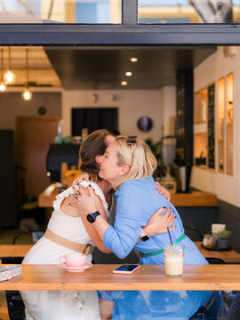 Friends Meet and Hug at a Cozy Cafe in the Afternoon