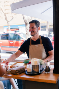 Coffee Shop Worker Serves Customers at a Busy Cafe
