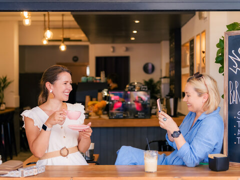 Woman taking photo of her friend at cafe 