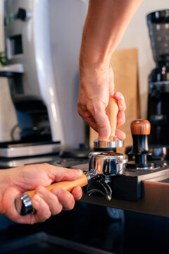 Barista tamping ground coffee into portafilter 