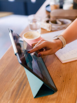 Woman using tablet computer at cafe on wooden table 