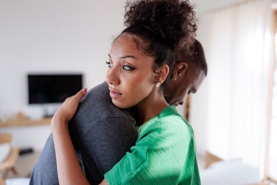 A woman hugs her partner, looking thoughtfully into the distance.