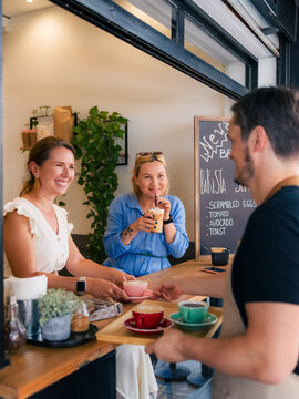 Waiter serving women at cafe 