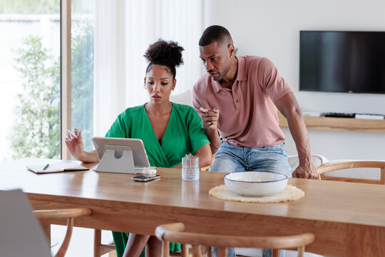 Couple working together on a digital tablet at home.