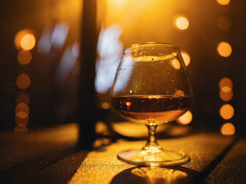 glass of cognac on beige background of banquet light in blur.
