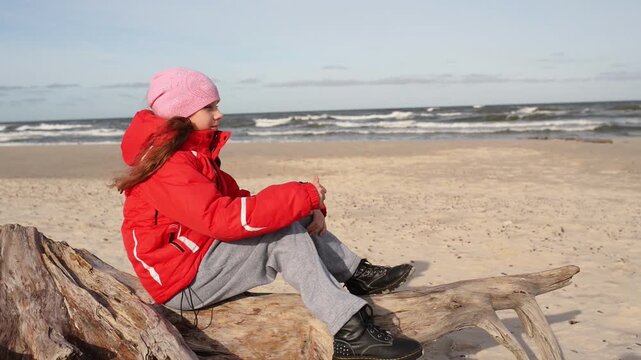 Little beautiful sad girl sits about sea