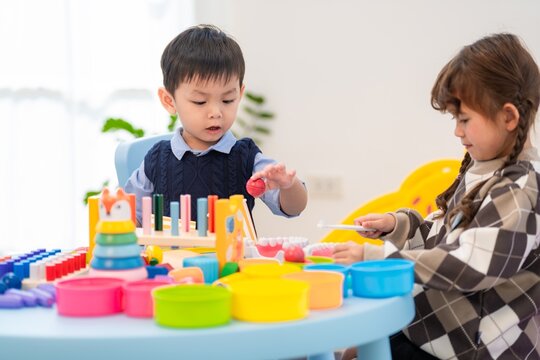 Children play with colorful toys at a table in a bright room during an afternoon activity session