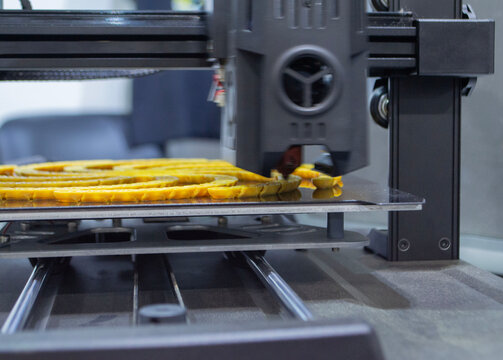 3D printer printing yellow model. Object printed on 3D printer from molten plastic yellow color. 3D printed object made from molten plastic. Additive modern manufacturing. 3D printing technology