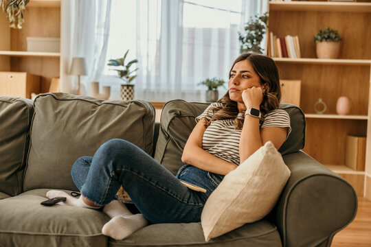 Woman resting on couch feeling pensive and bored at home