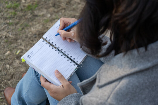 Woman writing daily planner for organization outdoors