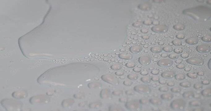 The surface is covered with water droplets, a light blue surface with many transparent water droplets of different diameters under soft light with a clear contour and organic detail.