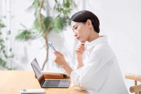 スマホを見て悩む女性