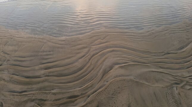 Ocean tide receding leaving textured sand patterns on a peaceful beach shore