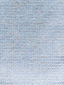 Textured light blue microfiber cloth covered in lint and dust particles. Macro view of a light blue textured cleaning fabric covered with dust specks, lint, and tiny stray fibers from household chores