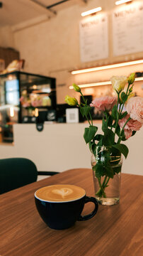 Aesthetic coffee cup with latte art and flowers in a cafe setting
