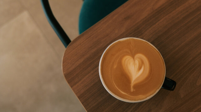 Cozy coffee break with latte art heart on a wooden table