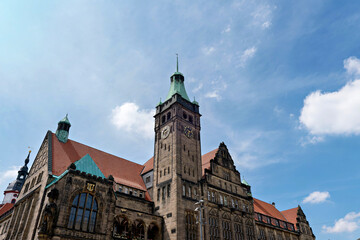 Obraz premium Historical town hall building with a prominent clock tower under a blue sky
