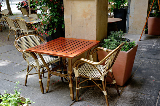 Small wooden table and two checkered chairs at outdoor restaurant corner
