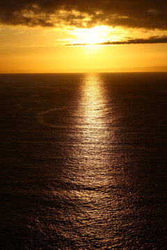 Golden sunlight breaking through dramatic clouds above the Atlantic Ocean at sunset
