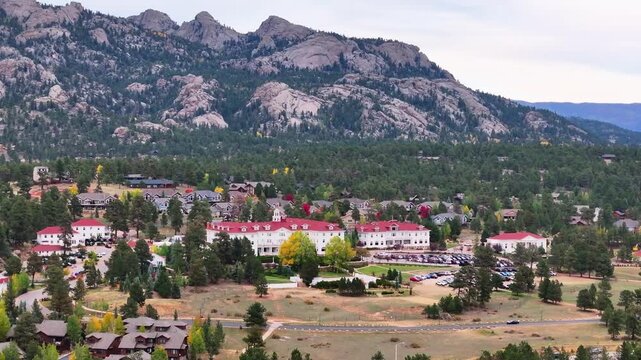 Panoramic aerial view of the historic Stanley Hotel in Estes Park, Colorado town with fall foliage colors and surrounding mountain landscapes during the autumn season - 4K Drone