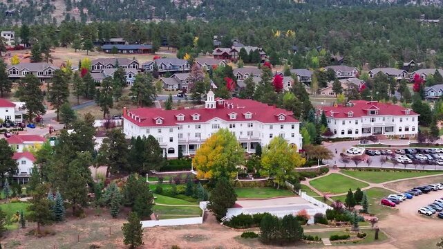 Panoramic aerial view of the historic Stanley Hotel in Estes Park, Colorado town with fall foliage colors and gateway to Rocky Mountain National Park landscapes during the autumn season - 4K Drone