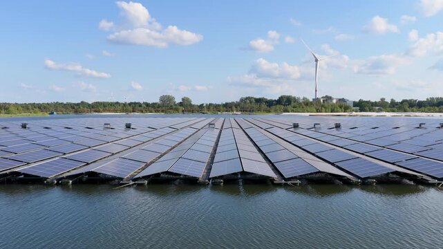 Aerial drone view of a floating solar panel farm on a calm lake surface. Modern green technology facility producing clean renewable energy on water.