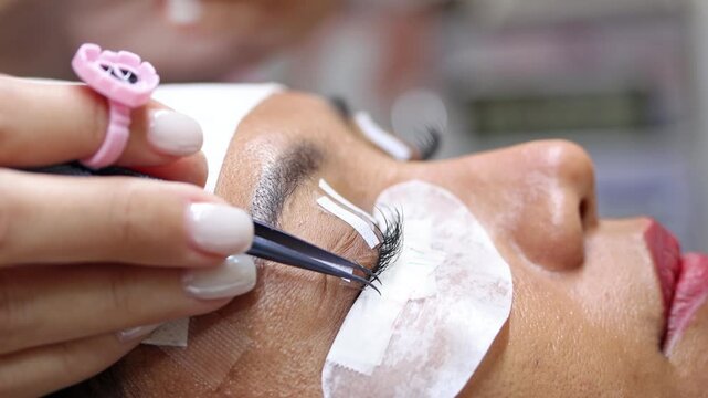 The process of eyelash extension and volume increase in a professional beauty salon, close-up view
