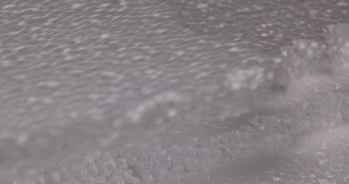 Textured white foam with rows of steps, porous foam consists of round elements and has a complex three-dimensional pattern of the material.