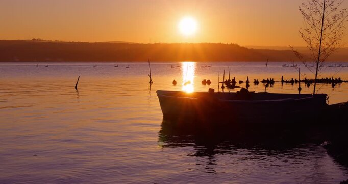 Sunset Over Calm Lake With Silhouetted Boat and Birds at Golden Hour