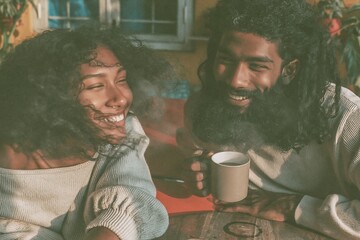 Fototapeta premium A happy young Indian couple laughing over coffee in a sunny home setting, featuring soft and film grain for lifestyle and leisure visuals