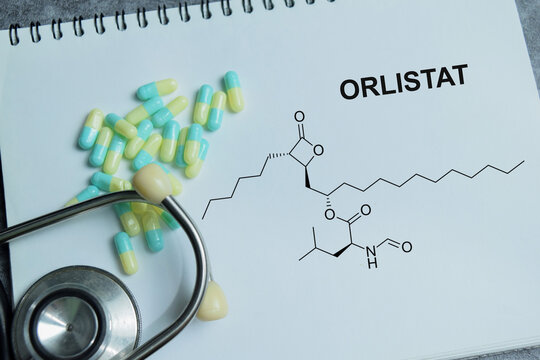 Concept of orlistat weight loss write on book isolated on Wooden Table. For obesity treatment and fat absorption inhibitor