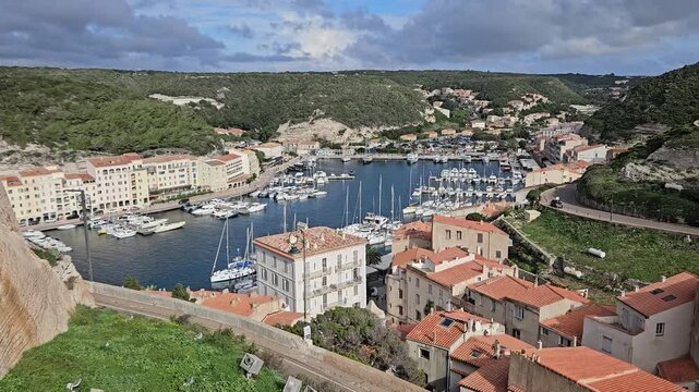 Yachts and sailboats moored in the Port de Bonifacio harbor basin, Corsica, France, seen from Montee Rastello, panning shot.