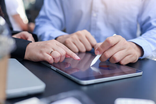 close up manager businesswoman hand point to report summary dashboard on digital tablet and consult or talk with colleague to planning strategy for financial management concept