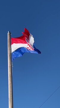 Croatian flag flying at the top of the mast on a sunny day.Blue sky in the background.Patriotic Symbol. Vertical 4k footage. Ideal format for social media postings and stories