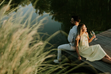 Fototapeta premium Couple enjoying a serene evening by the water with drinks in hand