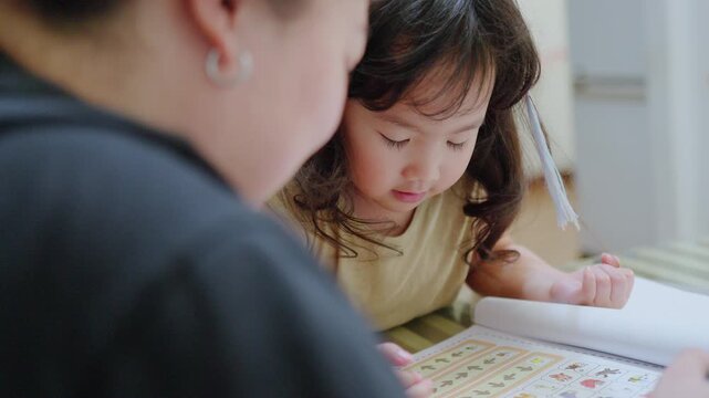 A curious toddler learns with her parent from a picture book, a moment of focused home education fostering early childhood development and cognitive skills.