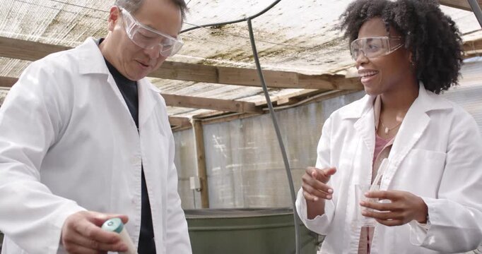 Diverse researchers in lab coats at tank inserting probe, making bubbles and pipetting for test