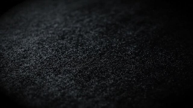 Black textured surface with subtle light reflections for minimalist video background and overlays